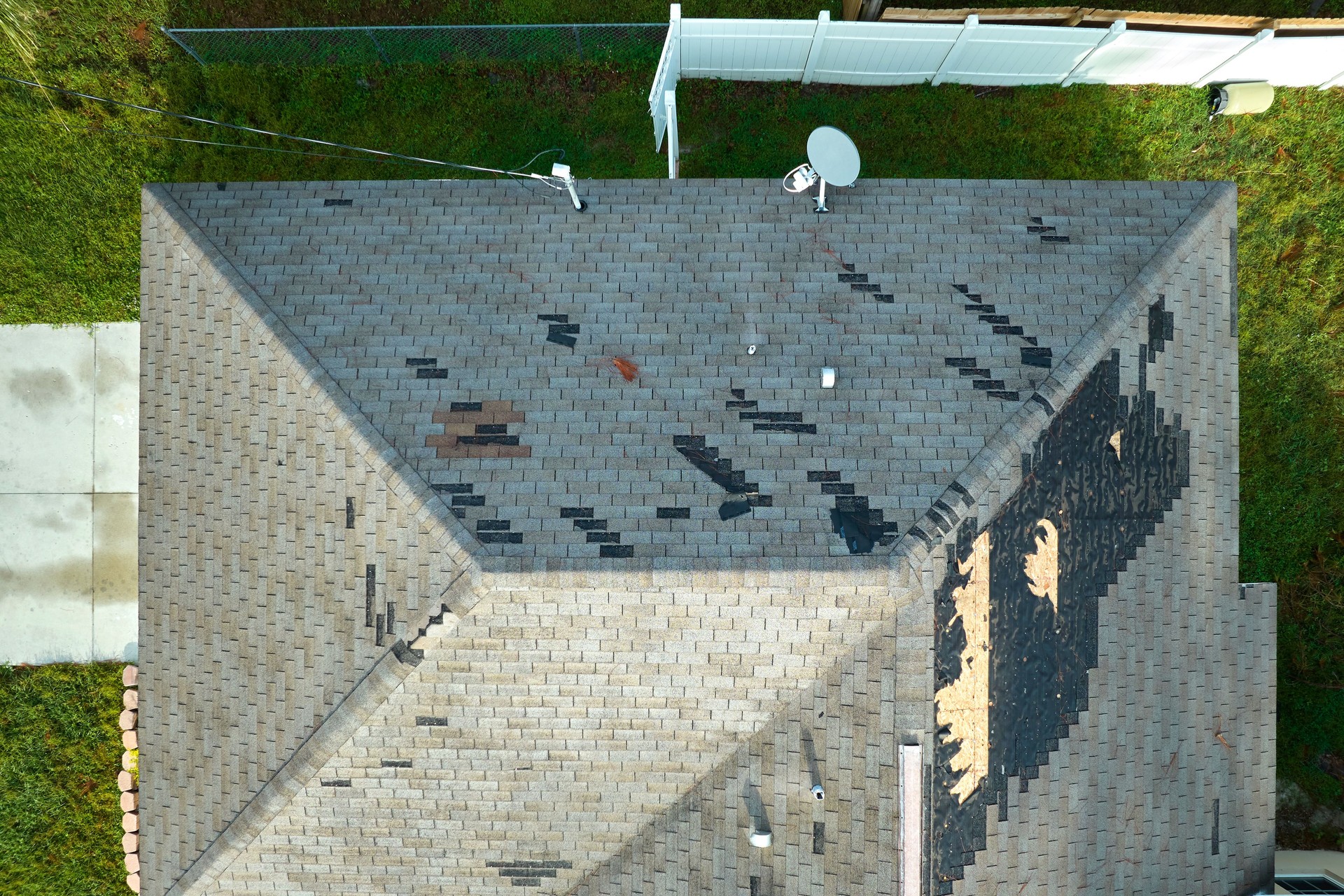 Wind damaged house roof with missing asphalt shingles after hurricane Ian in Florida. Repair of home rooftop concept